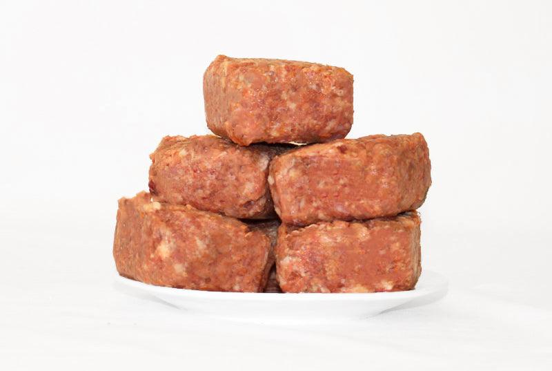 Puppy Mince 1kg portion pack stacked on white plate with chicken, beef, roo meat blend.