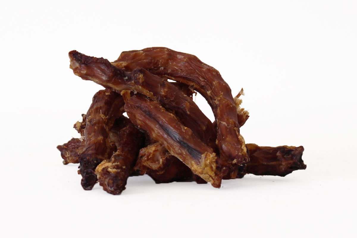 Pile of dried chicken necks dog treats on white background