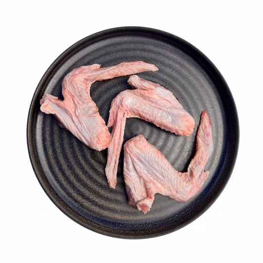 Three raw duck wings arranged on a round dark gray textured ceramic plate against a solid white background.