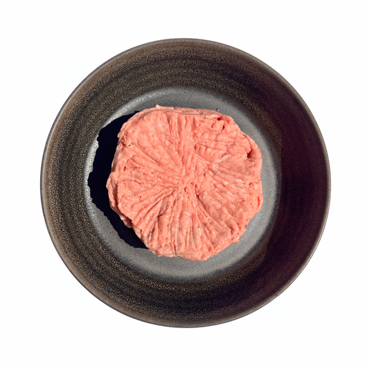 Chicken & Roo Mince in a pink, finely ground portion with a ridged, pressed surface on a dark ceramic plate.