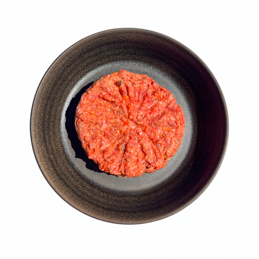 Chicken & Veggie Mince, pink raw ground meat with green and orange vegetable flecks shaped into a round mound