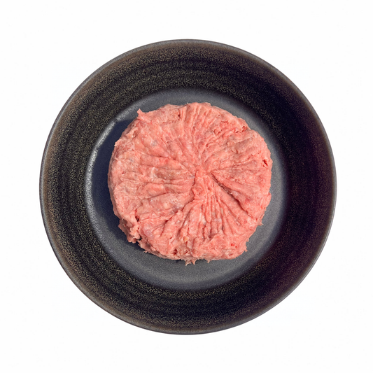 Raw mince roll, pink-red and coarsely textured; Mixed Meats blend pressed into a round shape.